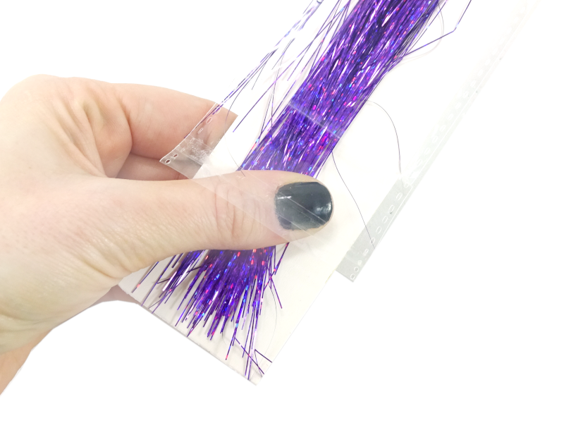 Holding the bottom of the tinsel in place while sliding the pack open to prevent tangling.